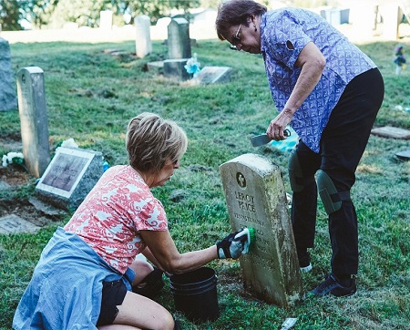 Two volunteers cleaning a headstone.
