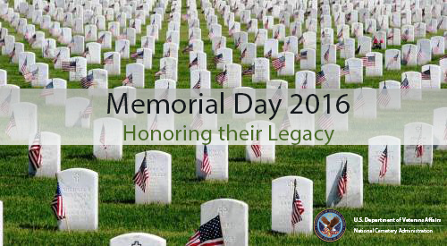 National Cemetery burial section with upright headstones decorated with miniature U.S. flags.