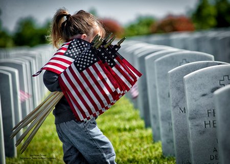 Young girl places Memorial Day flags at Sacramento Valley National Cemetery.