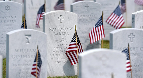 Small American flags placed in the ground in front of headstones on Memorial Day at Jacksonville National Cemetery in Florida.